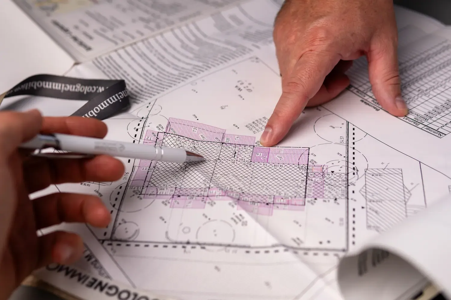 Nahaufnahme eines Schreibtisches mit Plänen eines Hauses und Materialien zur Berechnung verschiedener Werte